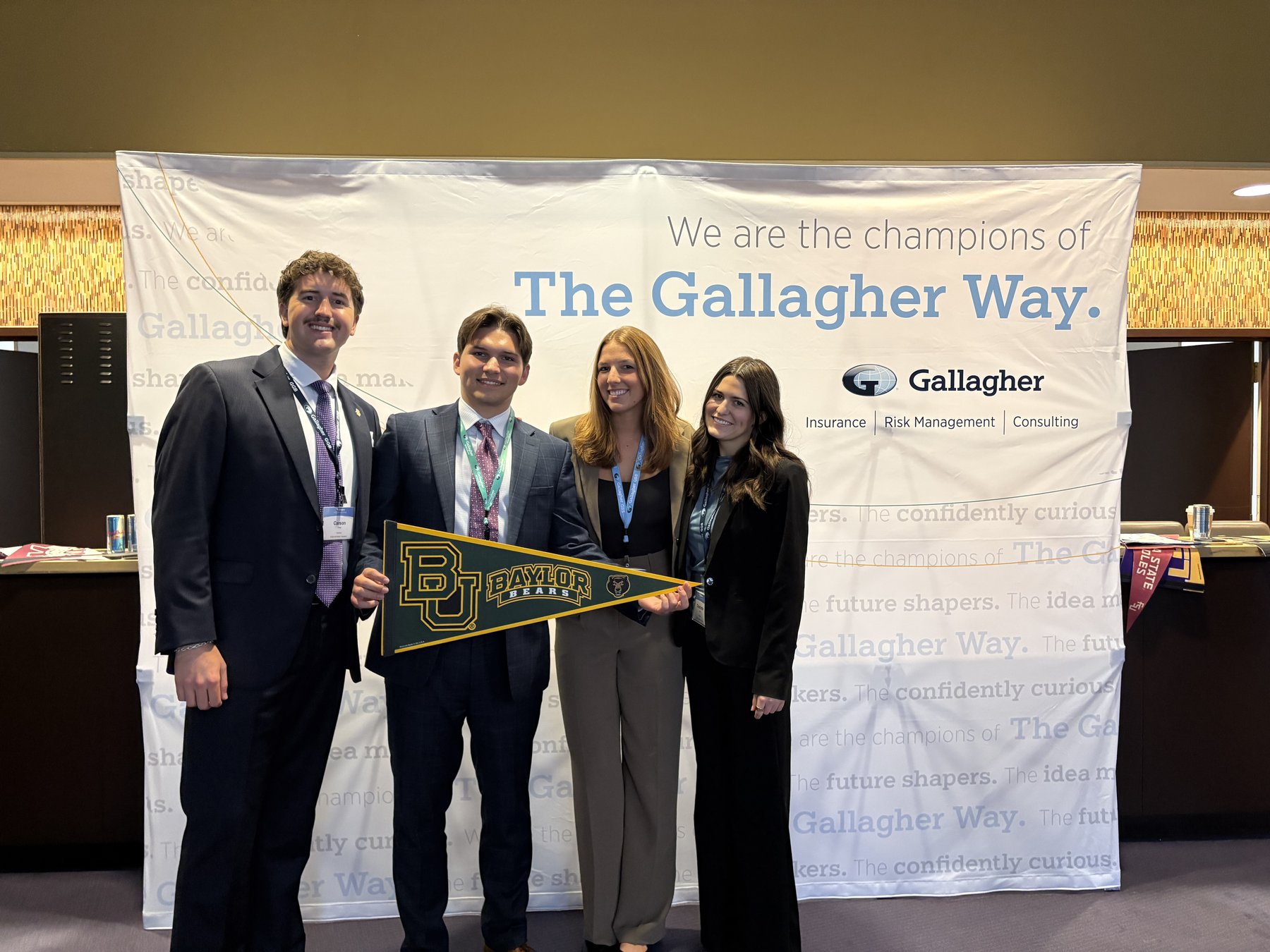 Cooper Carlsen with fellow Baylor interns at a Gallagher event, holding a Baylor pennant